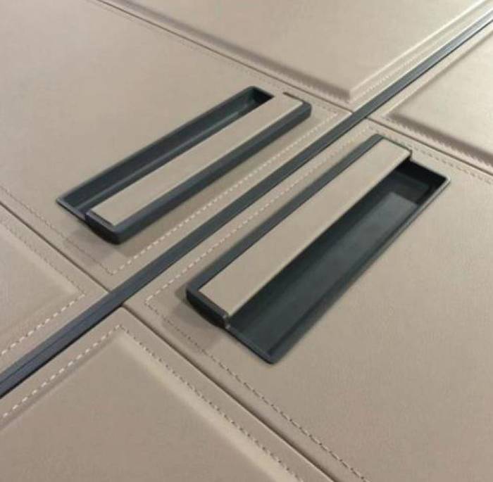 Recessed metal handle set into a leather-wrapped door