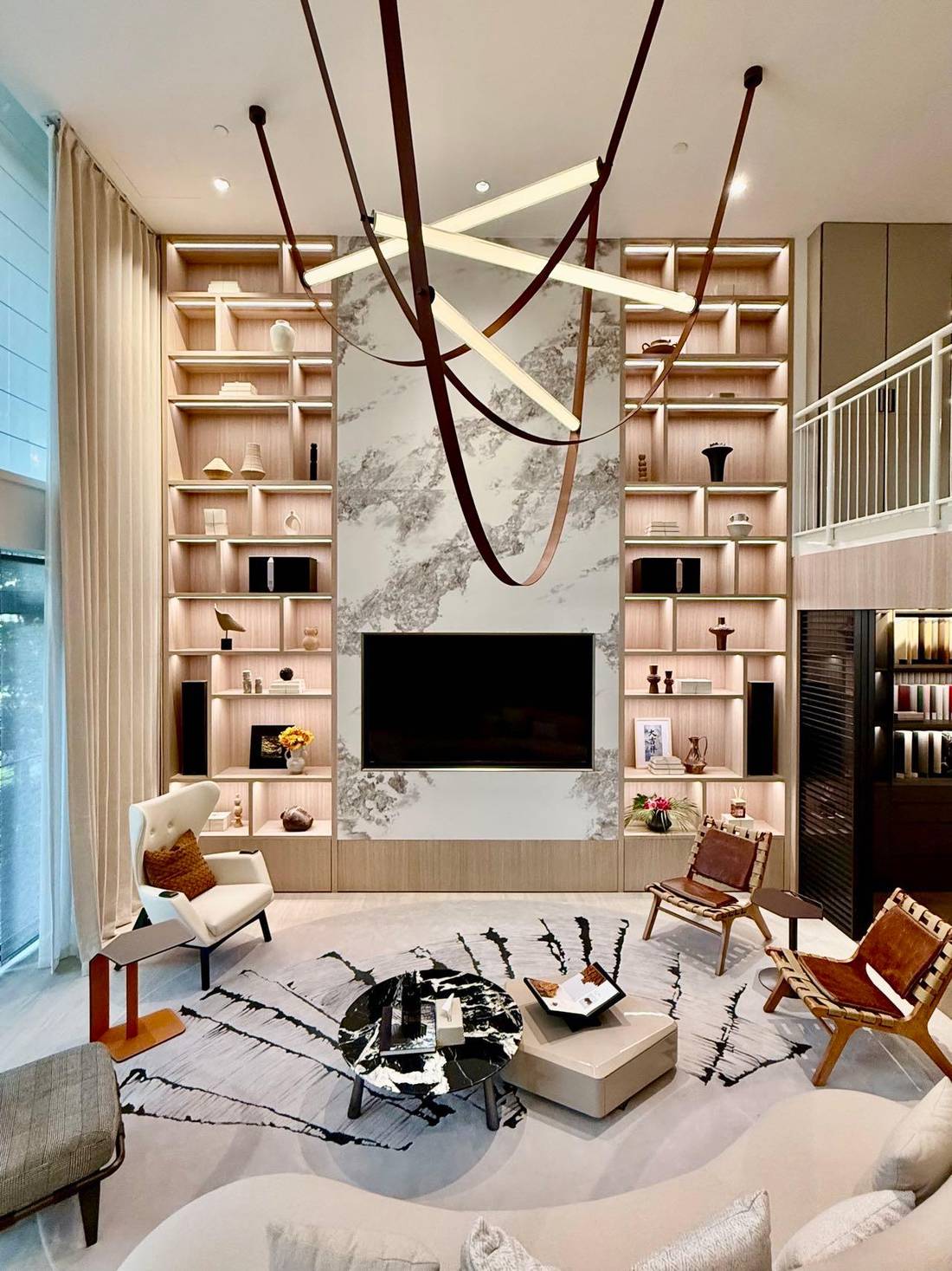 Double-height living room with full-height oak shelving and a marble feature wall